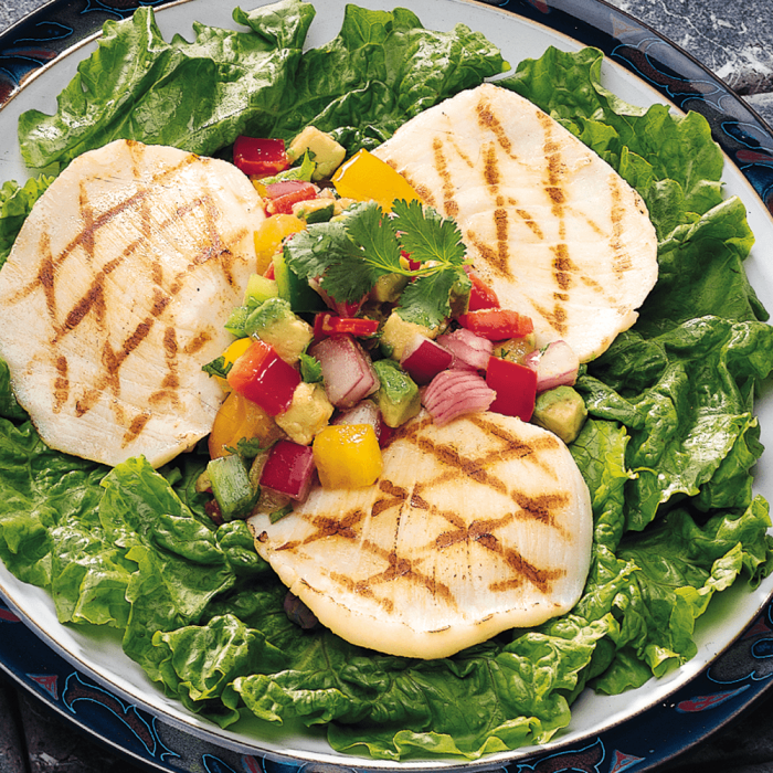 Fresh halibut cheeks displayed on a bed of ice in a seafood market.