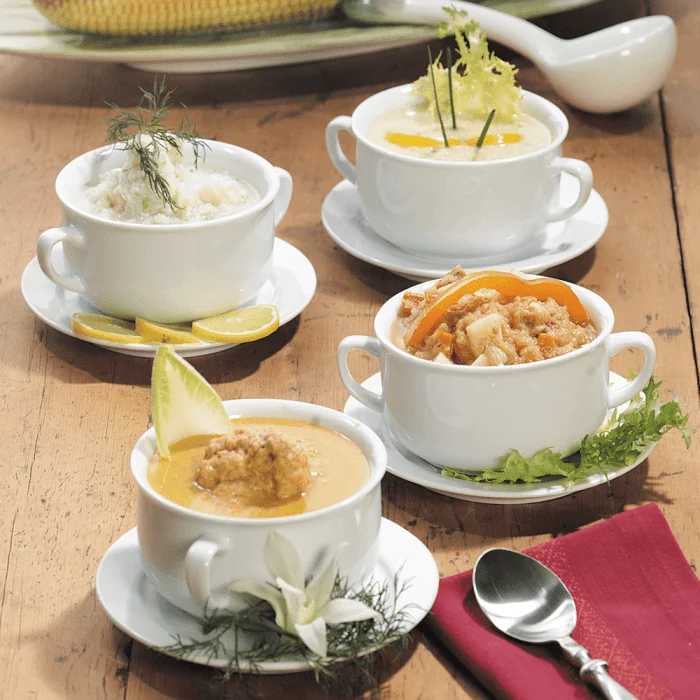 Four different types of soup served in individual bowls, arranged together for a diverse meal option.