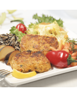 Two Dungeness crab cakes served on a white plate, garnished with fresh herbs and lemon slices.